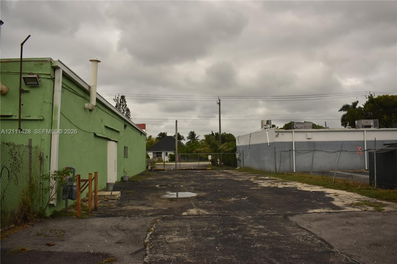 Paved exterior lot featuring metal-sided structures and chain-link fencing