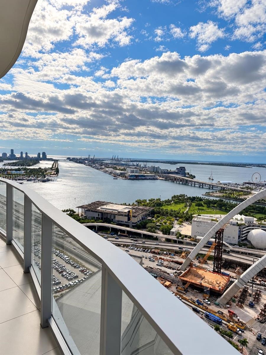 Private balcony with glass panel railing and panoramic waterfront and city skyline scenery