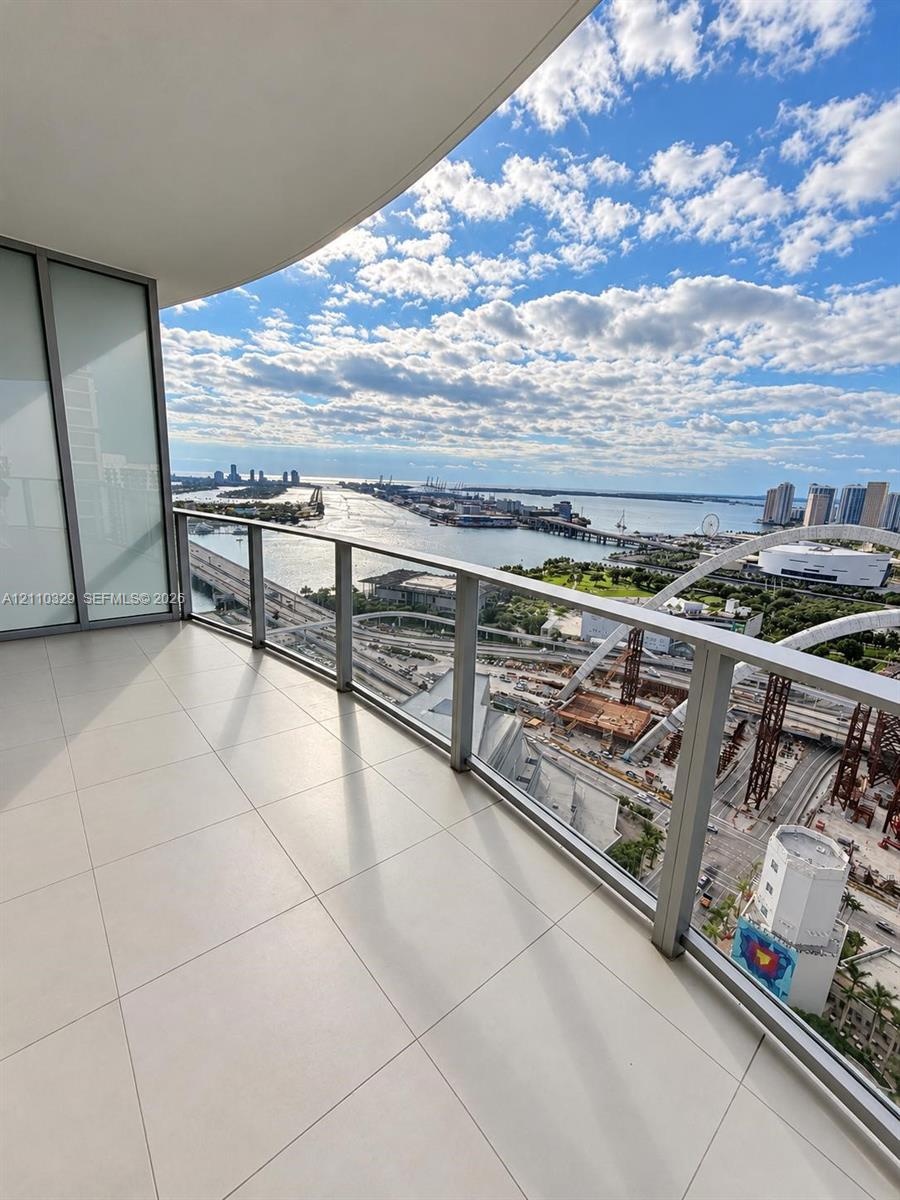 Covered balcony featuring large-format porcelain tile flooring and a glass panel railing