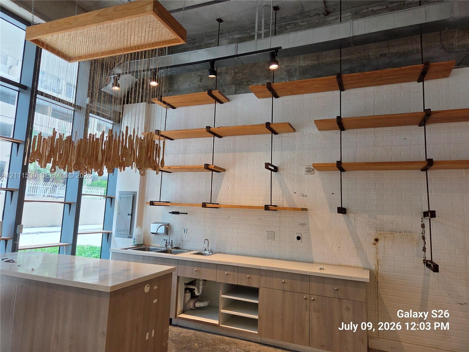 Floor-to-ceiling windows, wood-finish cabinetry, stone countertops, industrial-style suspended wood shelving, and exposed ceiling ductwork