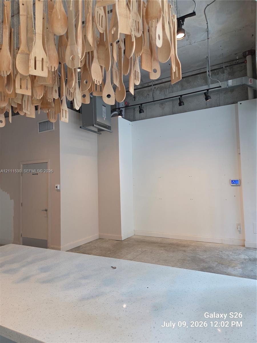 Industrial-style interior featuring exposed concrete ceilings, polished concrete flooring, track lighting, and a kitchen island with a white speckled 