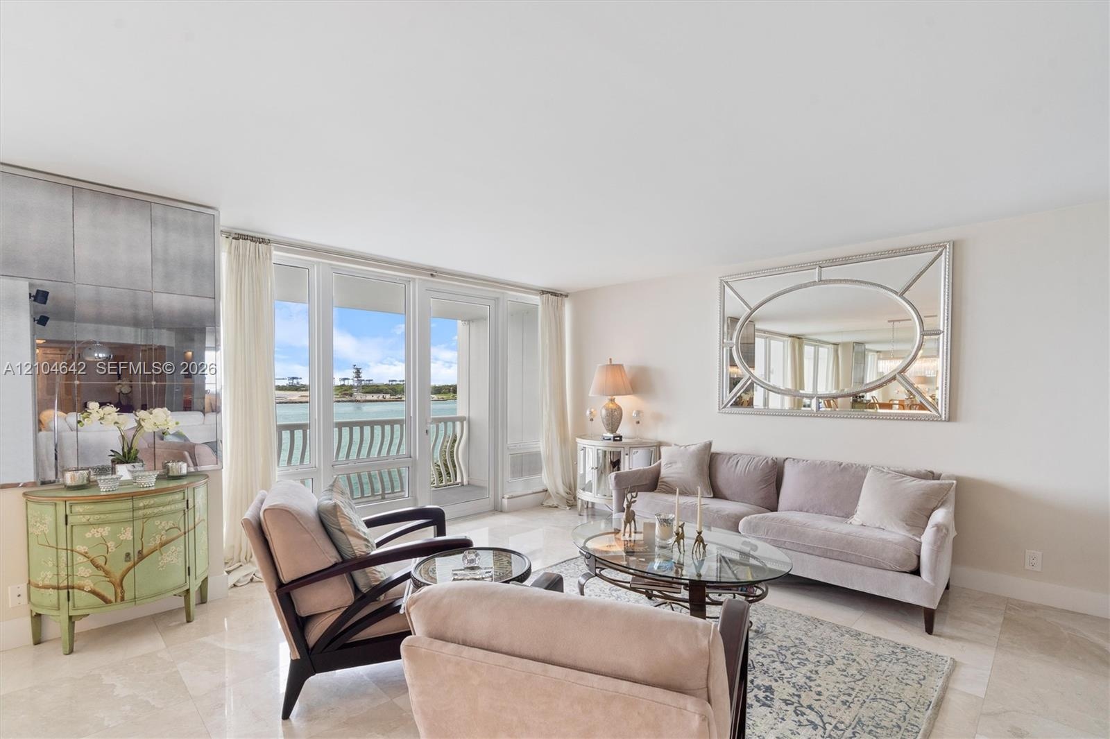 Living area featuring light-toned stone tile flooring, floor-to-ceiling glass panel windows, sliding glass door access to a balcony, and a mirrored wa