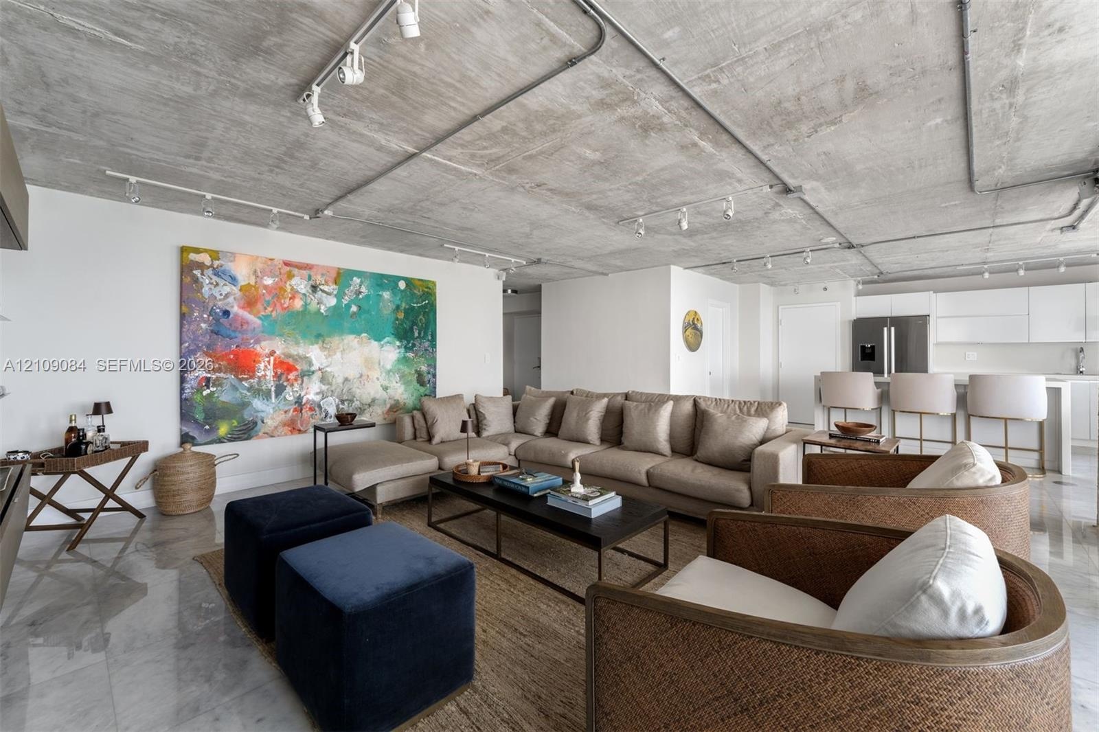 Industrial-inspired kitchen featuring an exposed concrete ceiling with surface-mounted conduit, high-gloss white cabinetry, stainless steel appliances