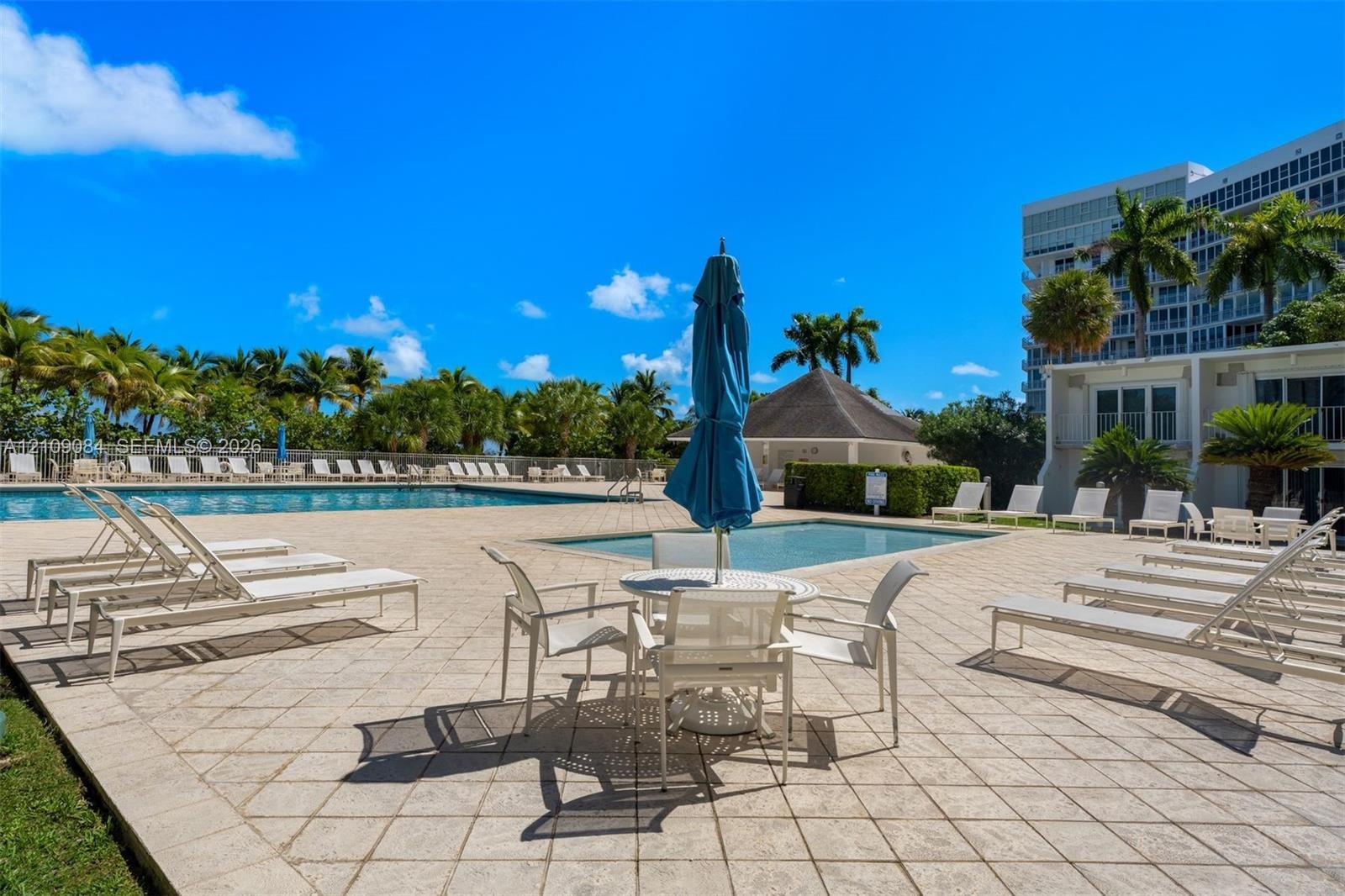 Exposed concrete ceilings, large-format tile flooring, wall-mounted track lighting, and full-height glass doors showcasing ocean scenery