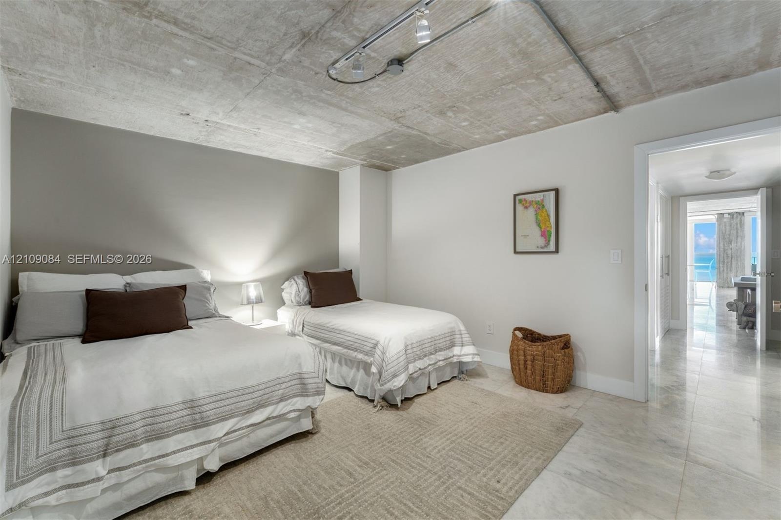 Exposed concrete ceiling with industrial-style surface-mounted track lighting, polished stone flooring, and high-gloss cabinetry