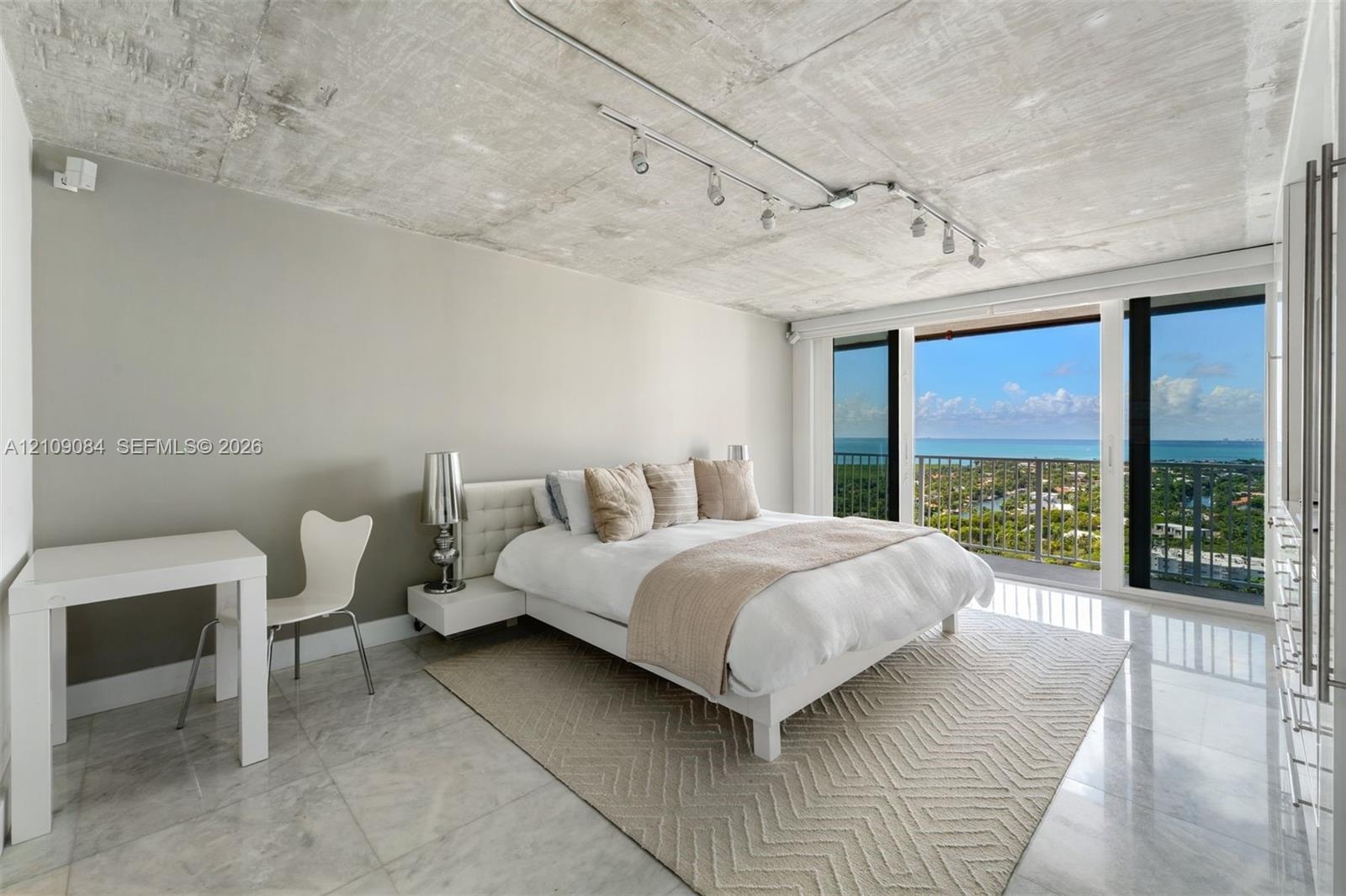 Industrial-style concrete ceiling, floor-to-ceiling glass wall, private balcony, and kitchen featuring an island with built-in cabinetry, complemented
