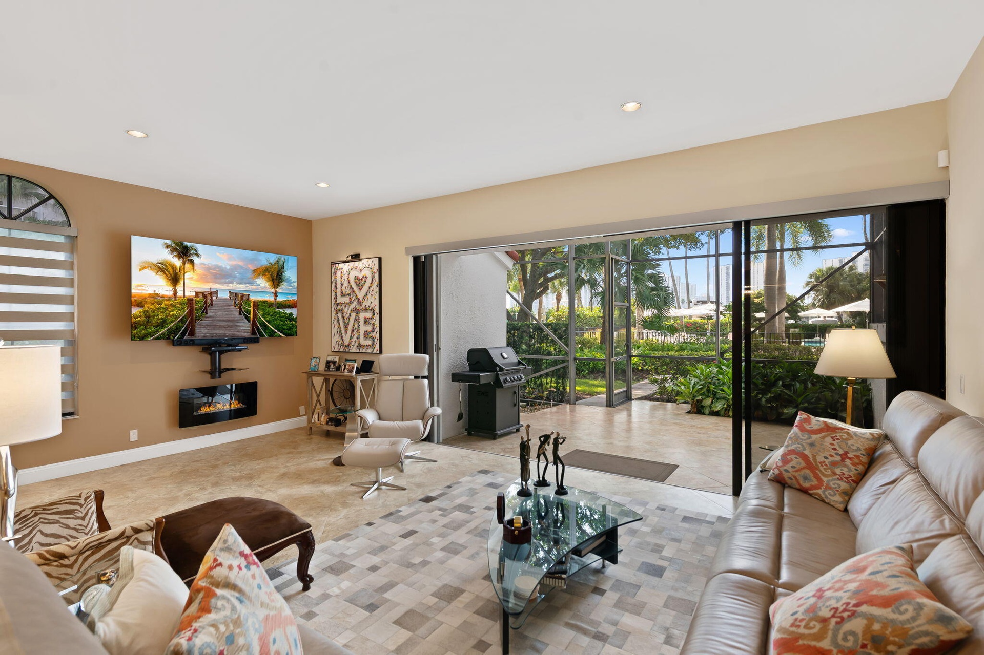 Living area featuring large-format tile flooring, recessed lighting, wall-mounted electric fireplace, and expansive multi-panel sliding glass doors op