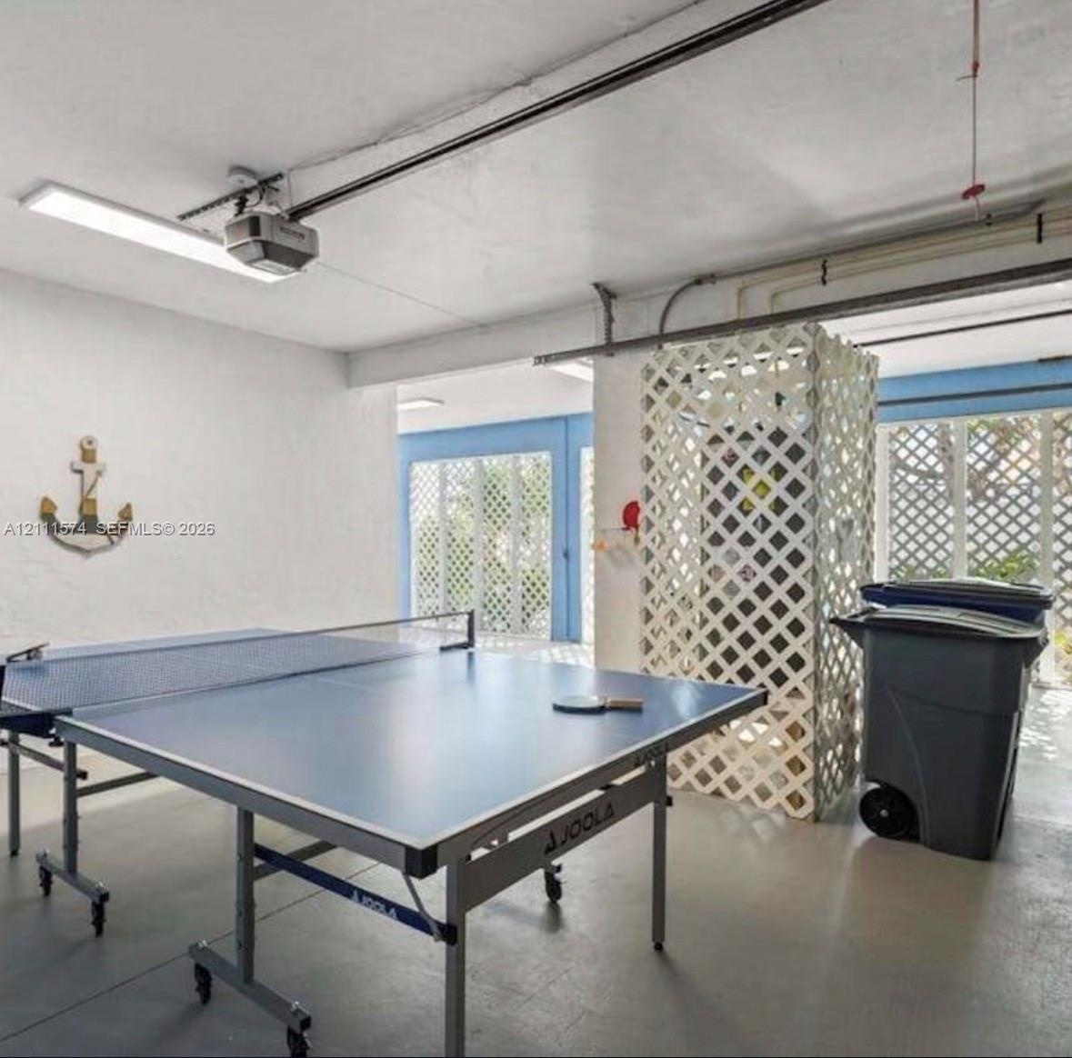Garage space featuring painted concrete flooring, integrated ceiling-mounted light fixtures, and white lattice partition detailing