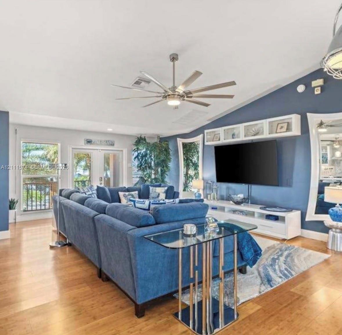 Vaulted ceiling featuring a multi-blade ceiling fan, expansive wood-finish flooring, and built-in upper wall cabinetry