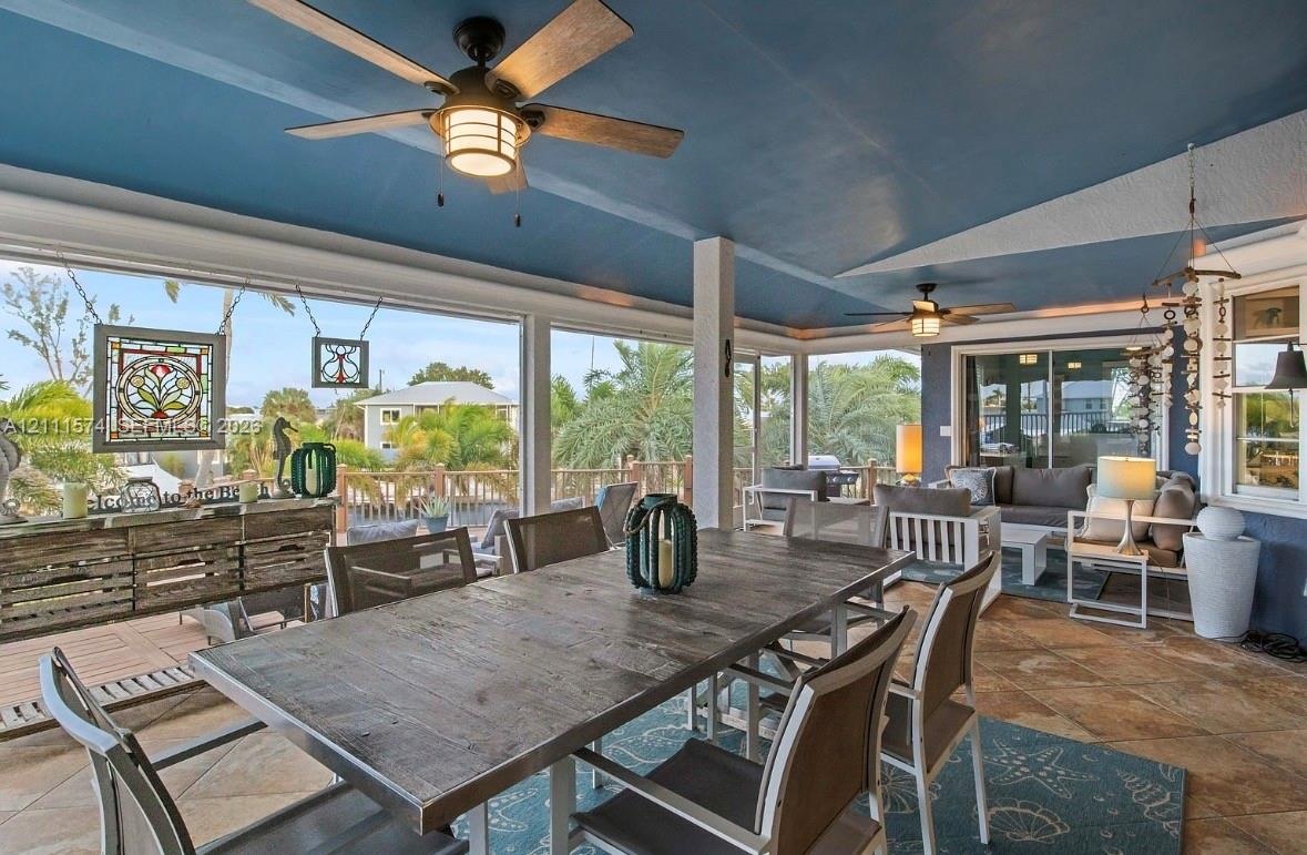 Covered outdoor living area featuring tile flooring, a painted vaulted ceiling, dual ceiling fans, and floor-to-ceiling screened enclosures