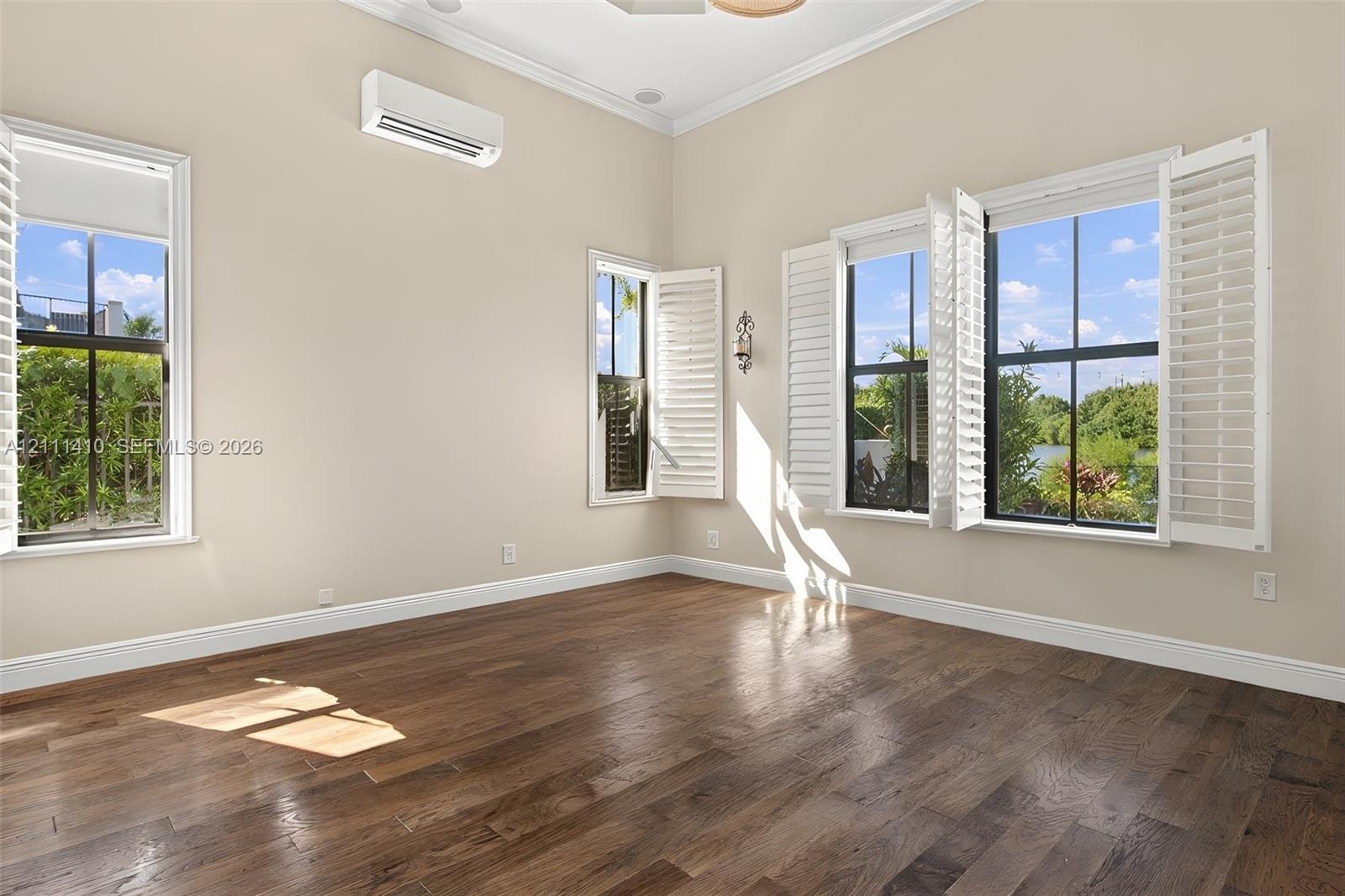Interior space featuring wood-finish flooring, vaulted ceilings, dual-pane windows with plantation shutters, and a wall-mounted ductless air condition