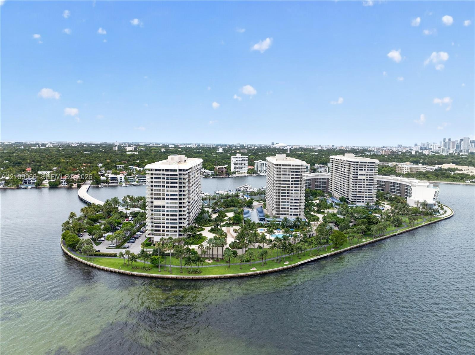 Waterfront high-rise community featuring landscaped grounds, palm tree-lined pathways, and expansive shoreline access