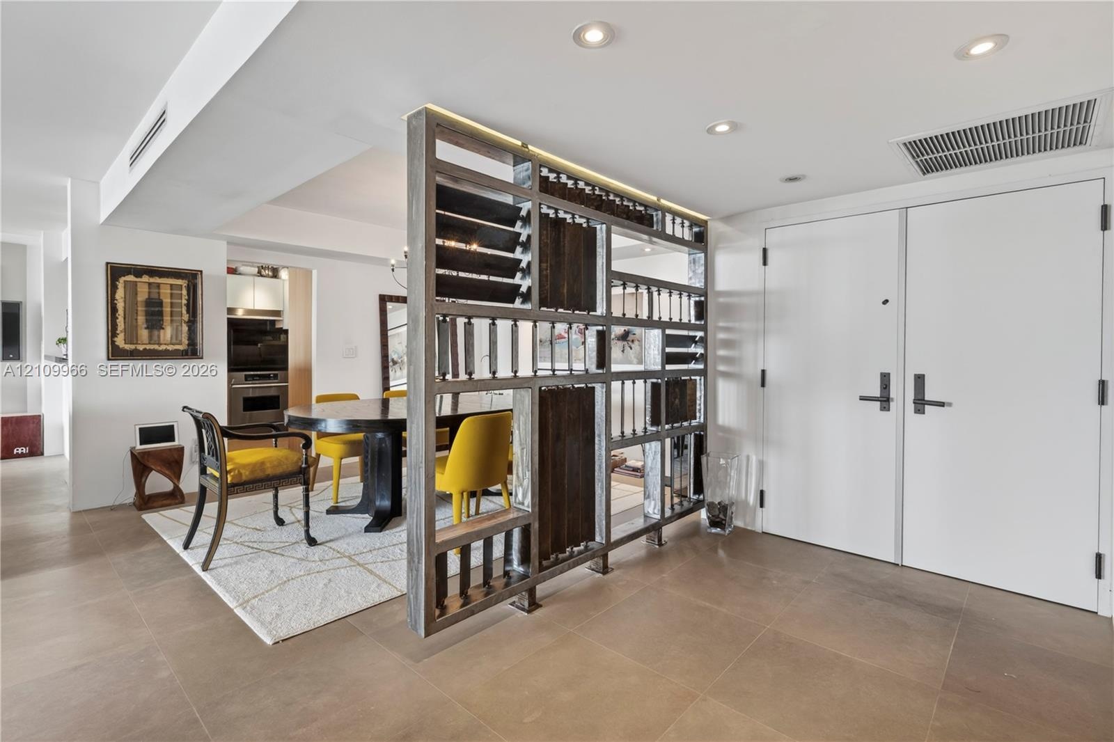 Custom wood-framed decorative partition, large-format tile flooring, recessed ceiling lighting, and double-entry doors