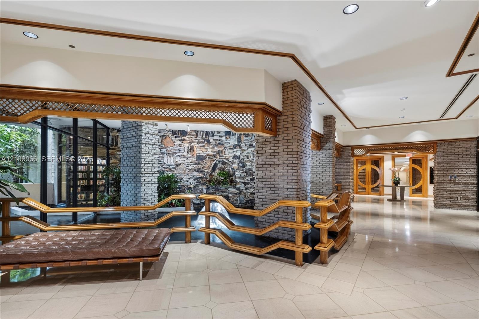 Interior featuring stone masonry pillars, tile flooring, recessed lighting, lattice woodwork accents, and a built-in water feature
