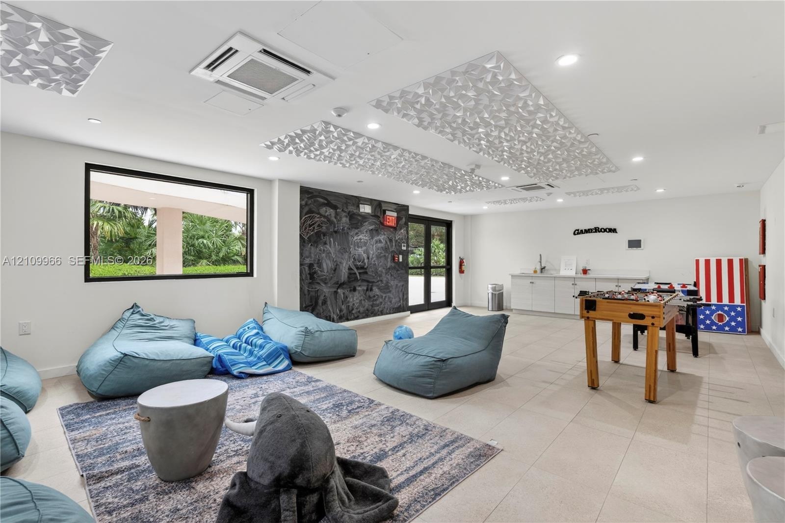 Spacious interior featuring recessed lighting, decorative ceiling acoustic panels, large-format tile flooring, a dark textured accent wall, and built-