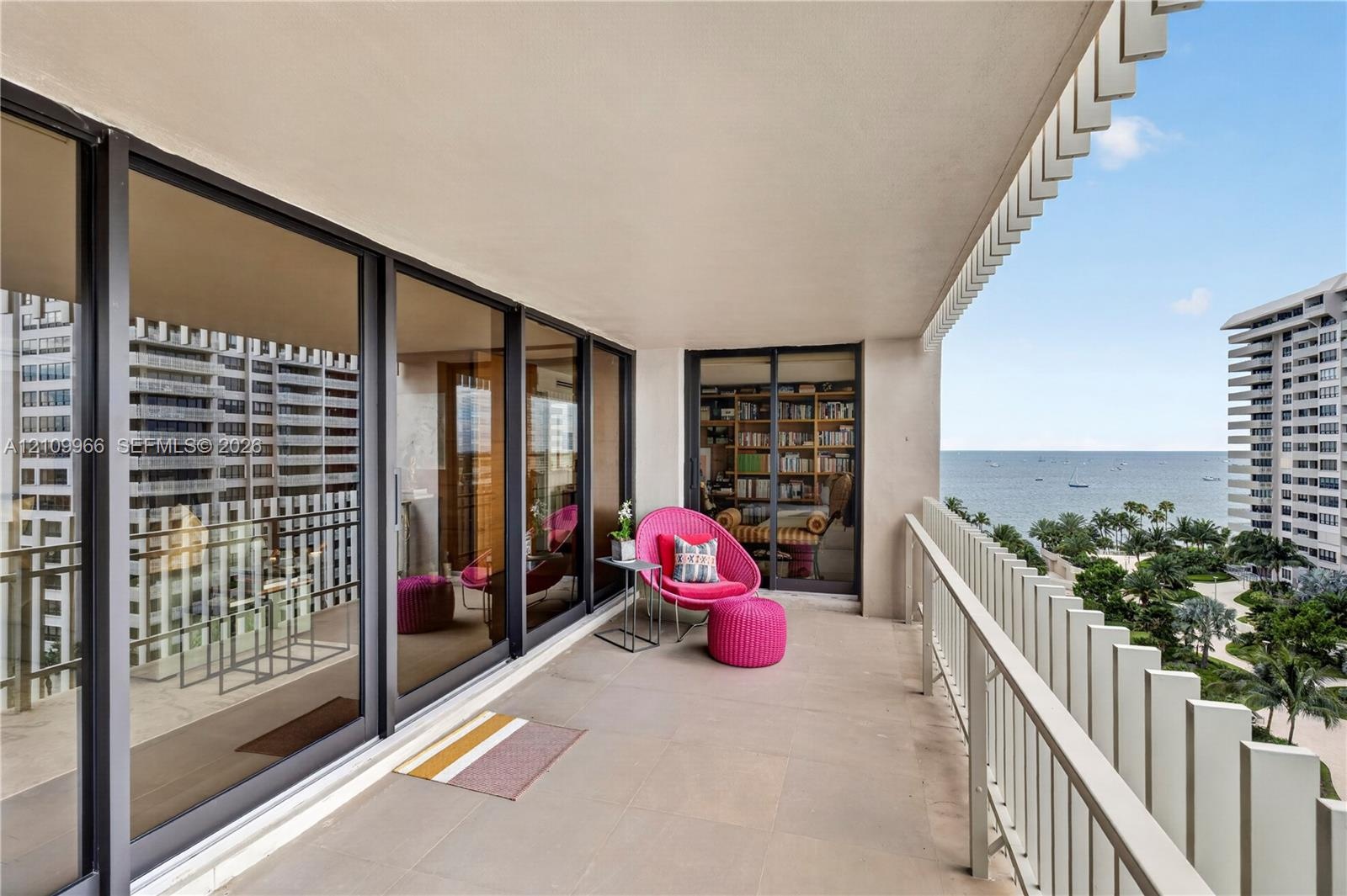 Covered balcony featuring concrete flooring, a white metal picket railing, and extensive floor-to-ceiling glass sliding doors