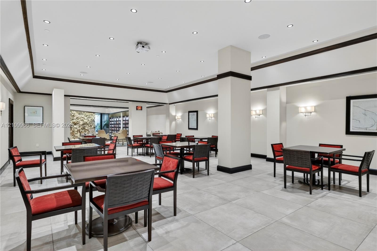Large common area featuring neutral tile flooring, recessed lighting, crown molding with dark wood trim, structural support columns, and wall-mounted 