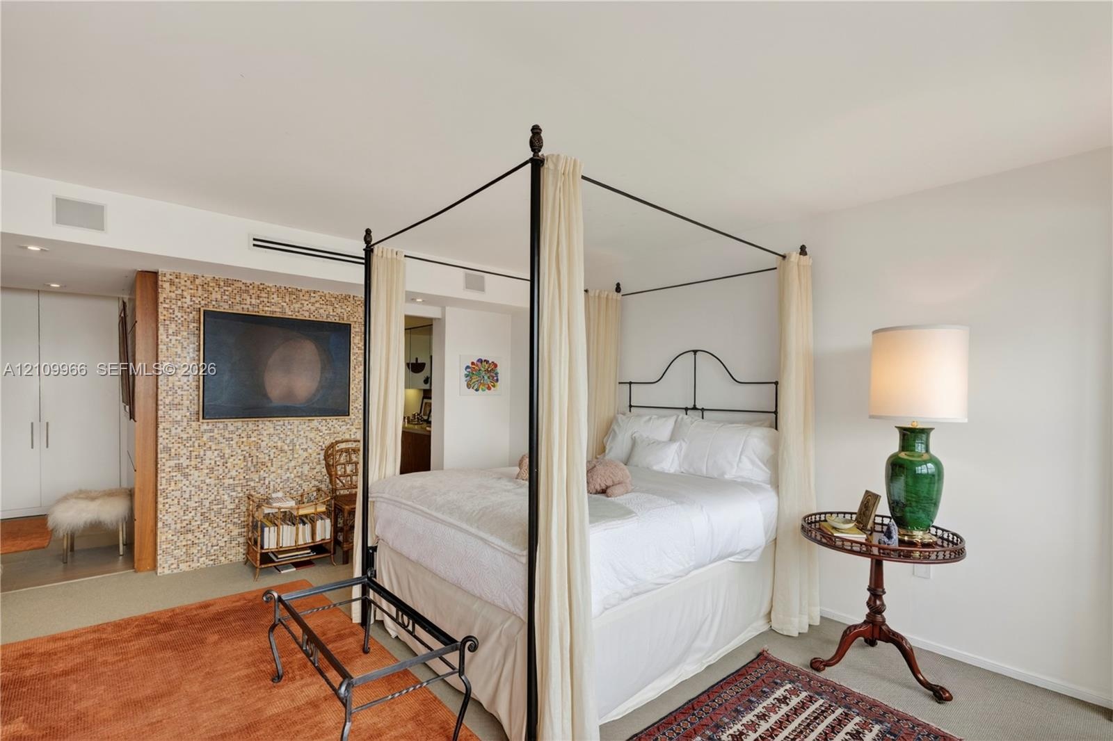 Textured accent wall, neutral carpeting, recessed ceiling lighting, and built-in closet cabinetry