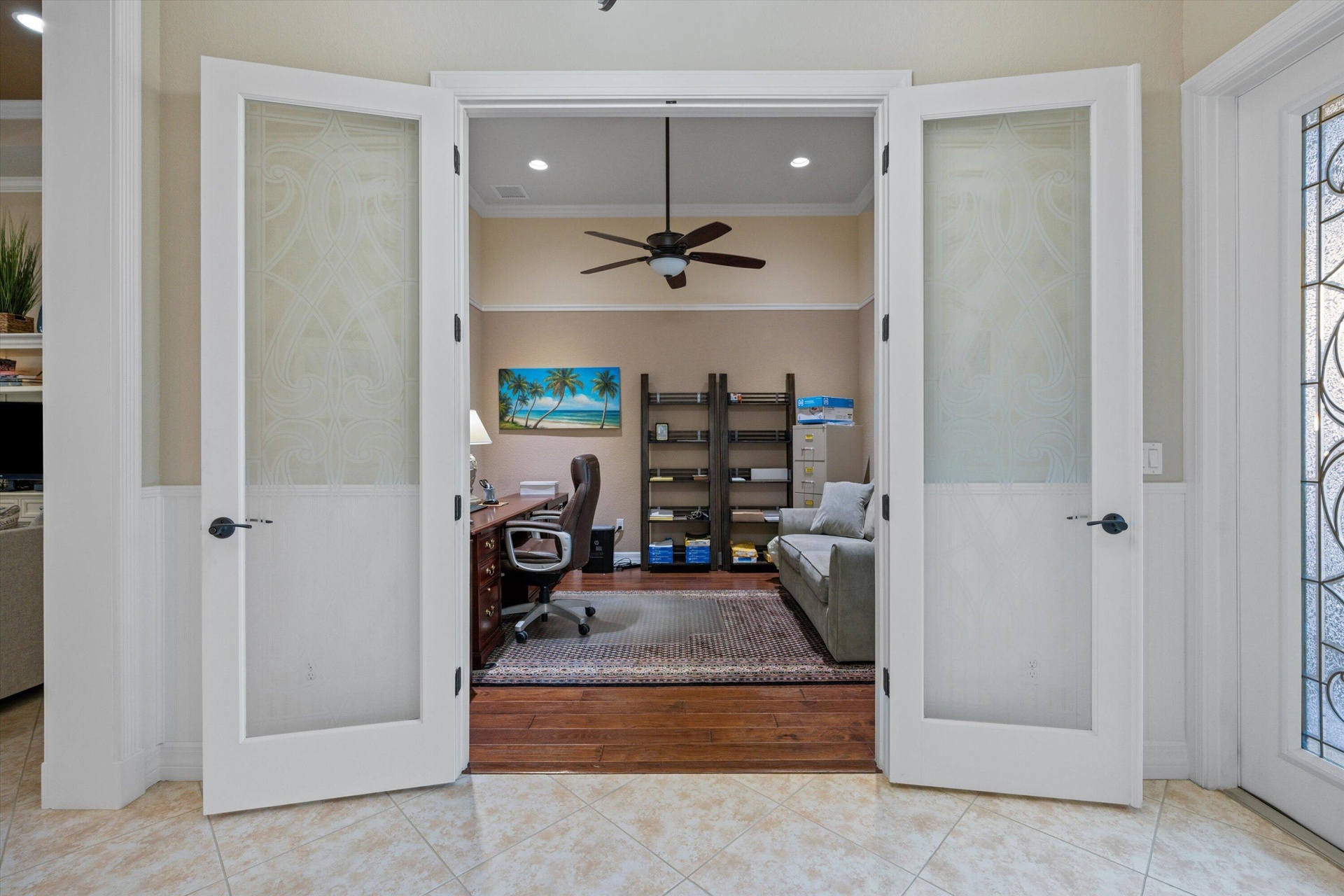 French-style double doors featuring frosted glass panels and dark hardware, wood-finish flooring, recessed lighting, and a ceiling fan