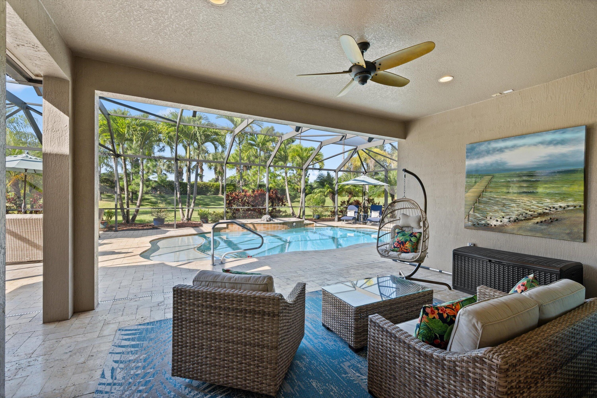 Covered lanai featuring paver flooring, a recessed ceiling with a central fan, and a screened enclosure surrounding a swimming pool