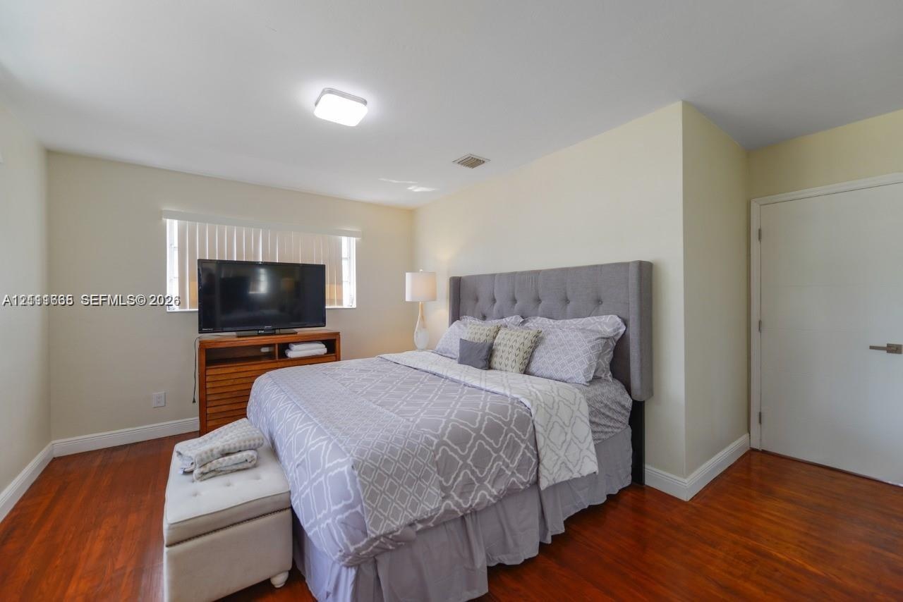 Room featuring wood-finish flooring, neutral wall paint, and a window with horizontal blinds