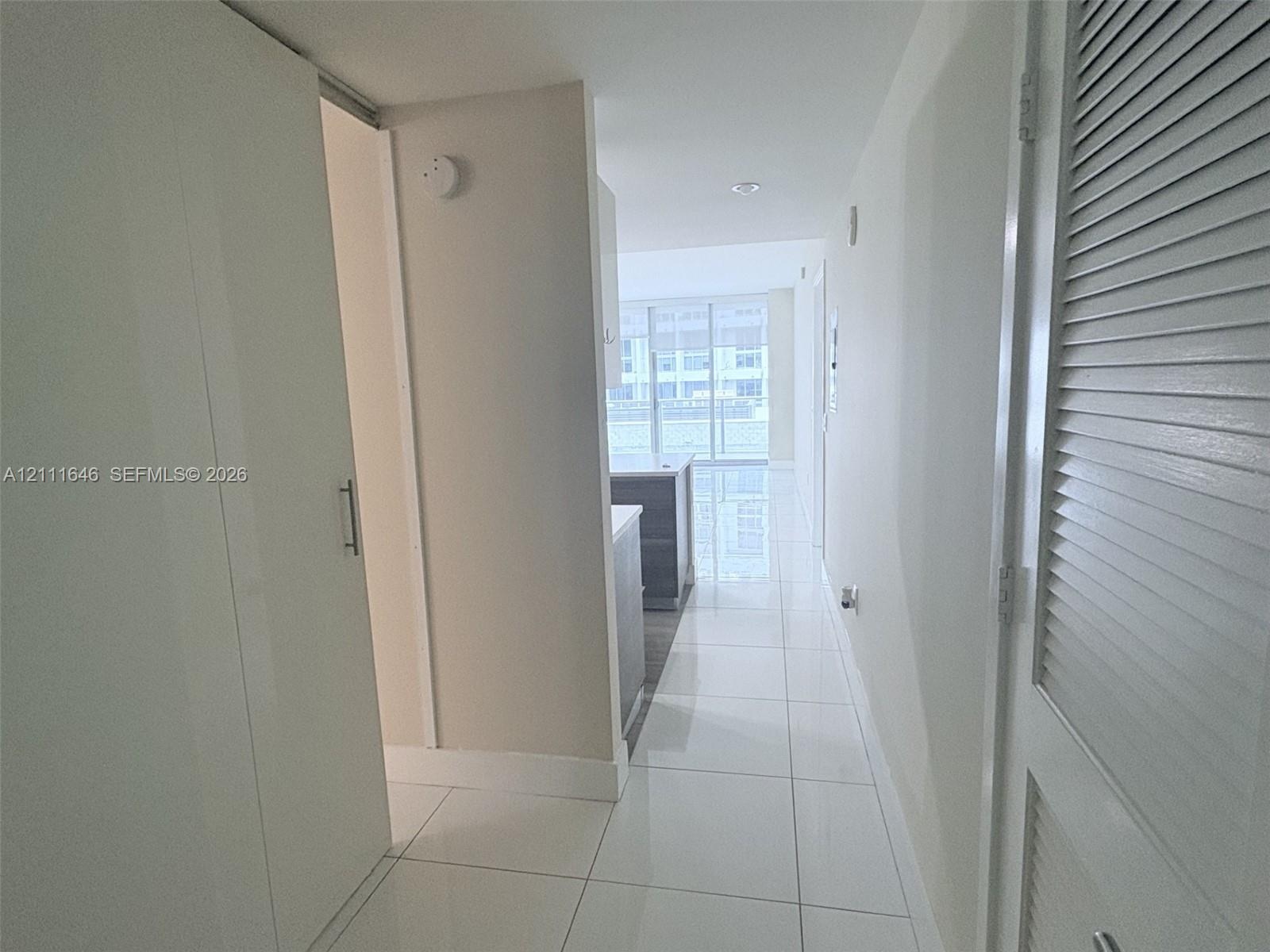 Glossy large-format tile flooring, recessed ceiling lighting, and louvered-panel closet doors