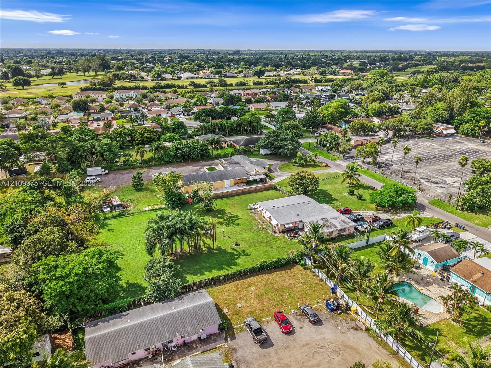 Expansive lot featuring a gravel driveway, mature trees, and open green space