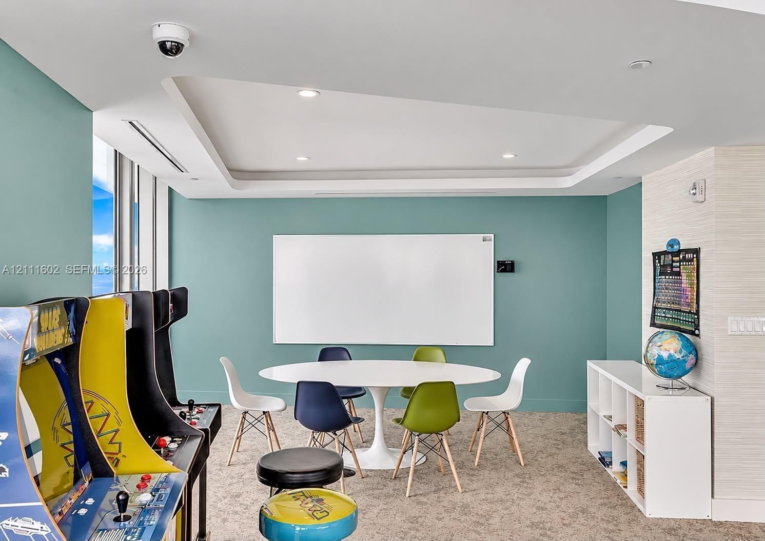 Tray ceiling with recessed lighting, wall-mounted whiteboard, and textured wall finish