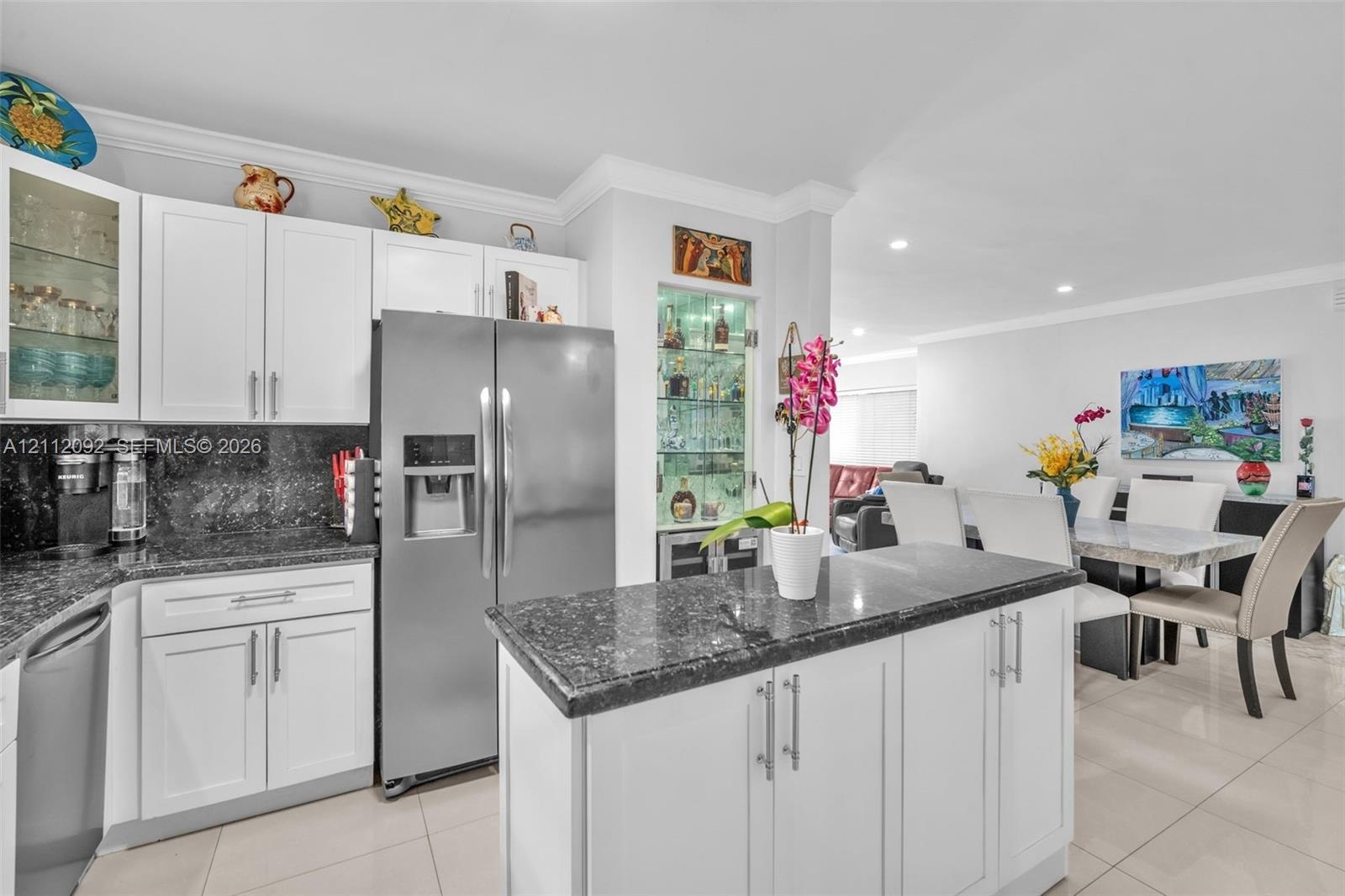 Kitchen featuring white shaker-style cabinetry, dark stone countertops, stainless steel appliances, a brass-toned gooseneck faucet, and a frosted glas