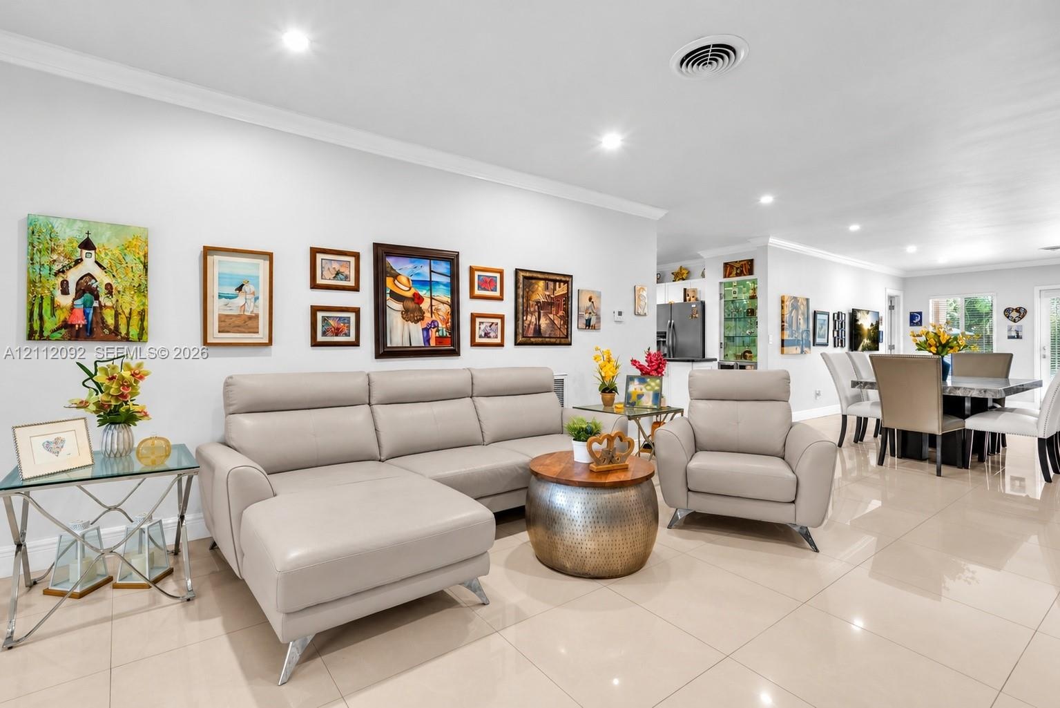 Open-concept floor plan featuring light-toned tile flooring, recessed lighting, and crown molding