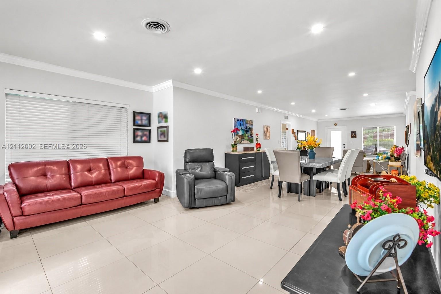 Kitchen featuring white shaker-style cabinetry, a central island with a stone-finish countertop, stainless steel microwave, integrated oven, and tile 