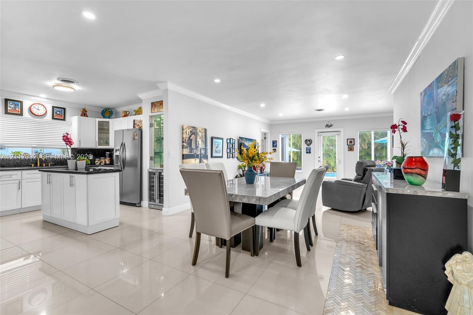 Open-concept interior featuring large-format tile flooring, recessed lighting, crown molding, and a glass-paneled exterior door