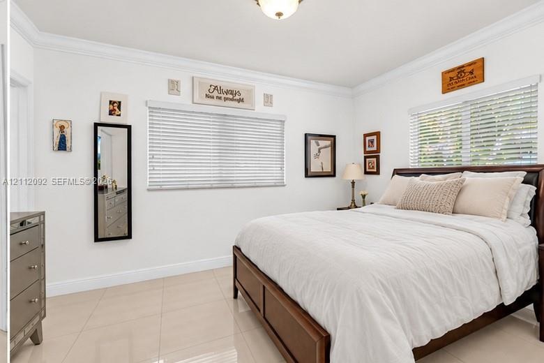 Open-concept interior featuring large-format tile flooring, recessed ceiling lighting, crown molding, and expansive windows with installed blinds