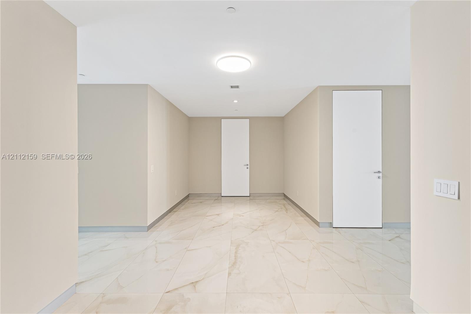Large-format light-toned tile flooring, neutral wall palette, flat-panel doors with metallic hardware, and flush-mount ceiling lighting
