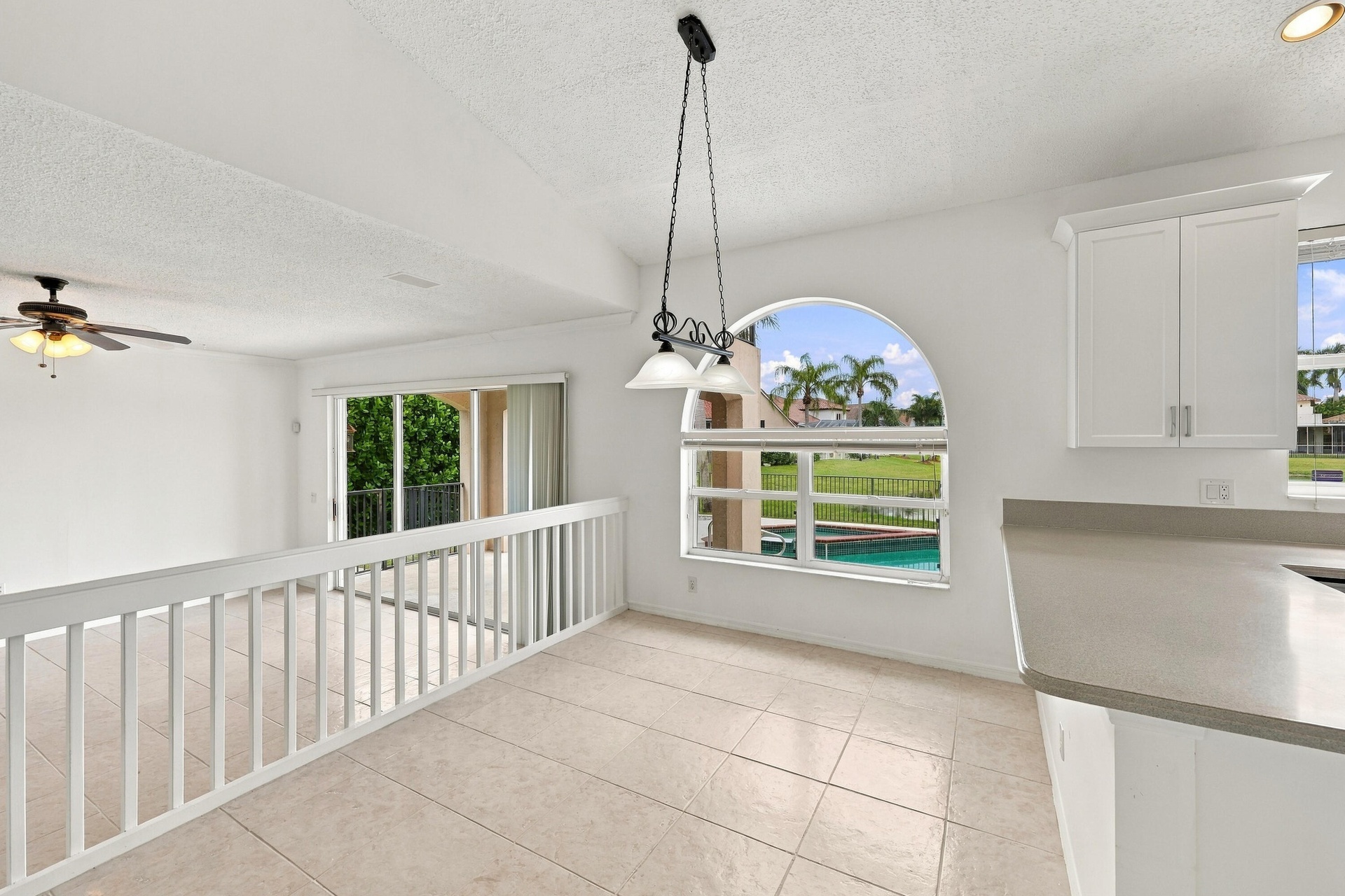 A wonderful setting for casual dining, this breakfast nook features an oversized arched window, decorative pendant lighting, and an open connection to