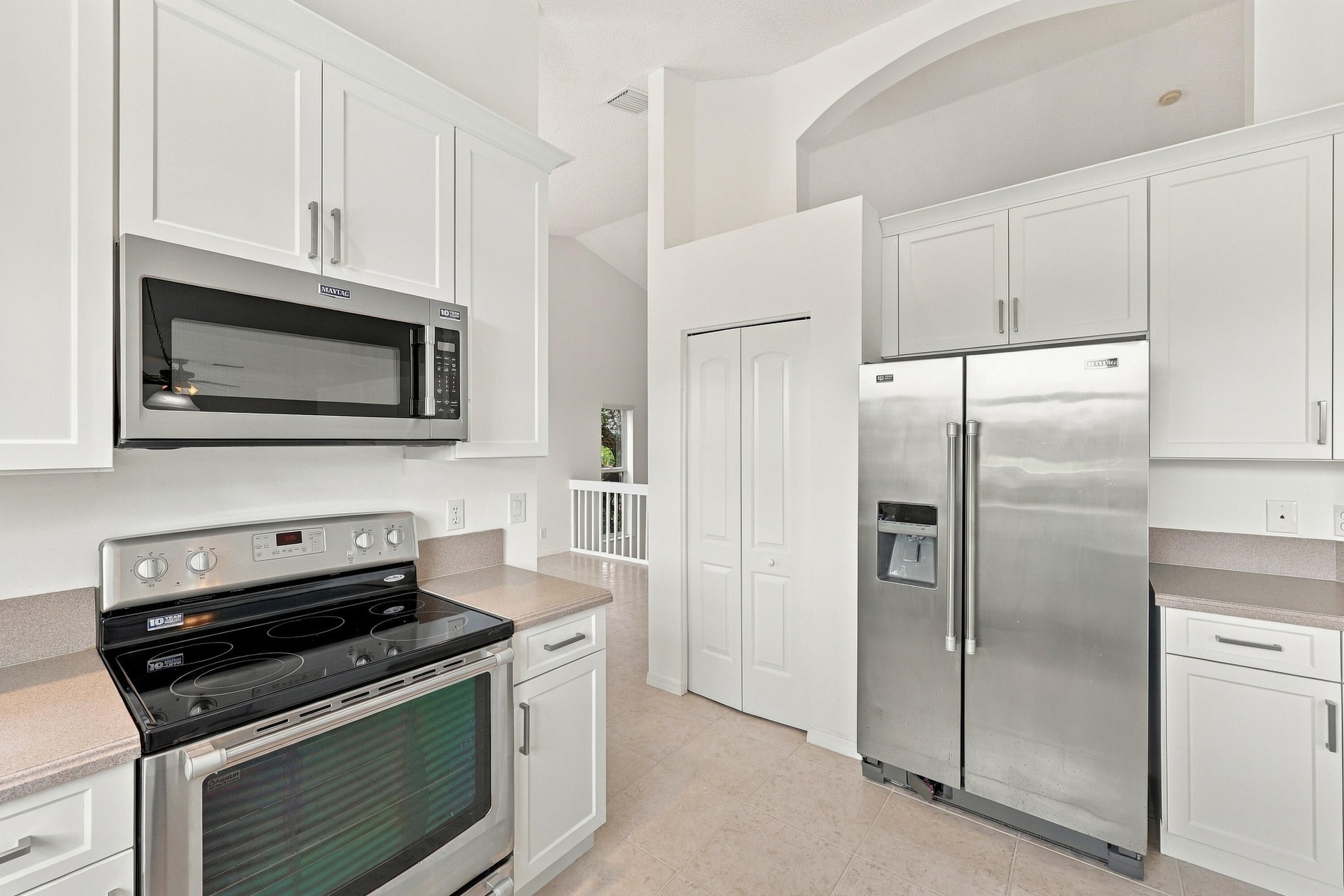 The kitchen features crisp white cabinetry, stainless steel appliances, ample storage, and a functional layout designed for everyday convenience.