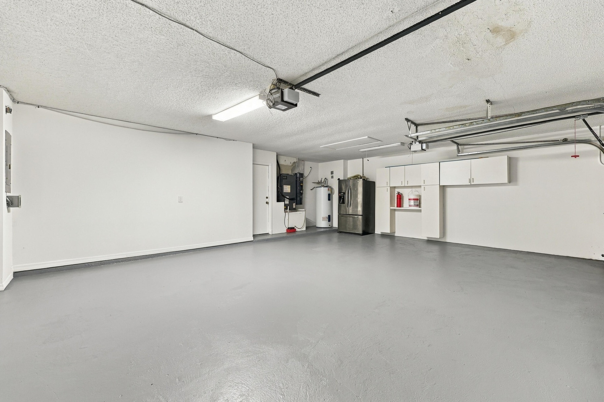 This oversized three-car garage features a finished floor, utility sink, and ample room for vehicles, recreational equipment, additional storage, or a