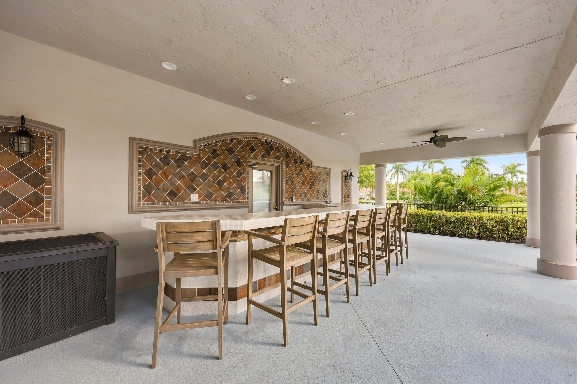 An inviting covered outdoor entertaining area featuring bar-style seating and ceiling fans, perfect for socializing and enjoying the beautiful South F