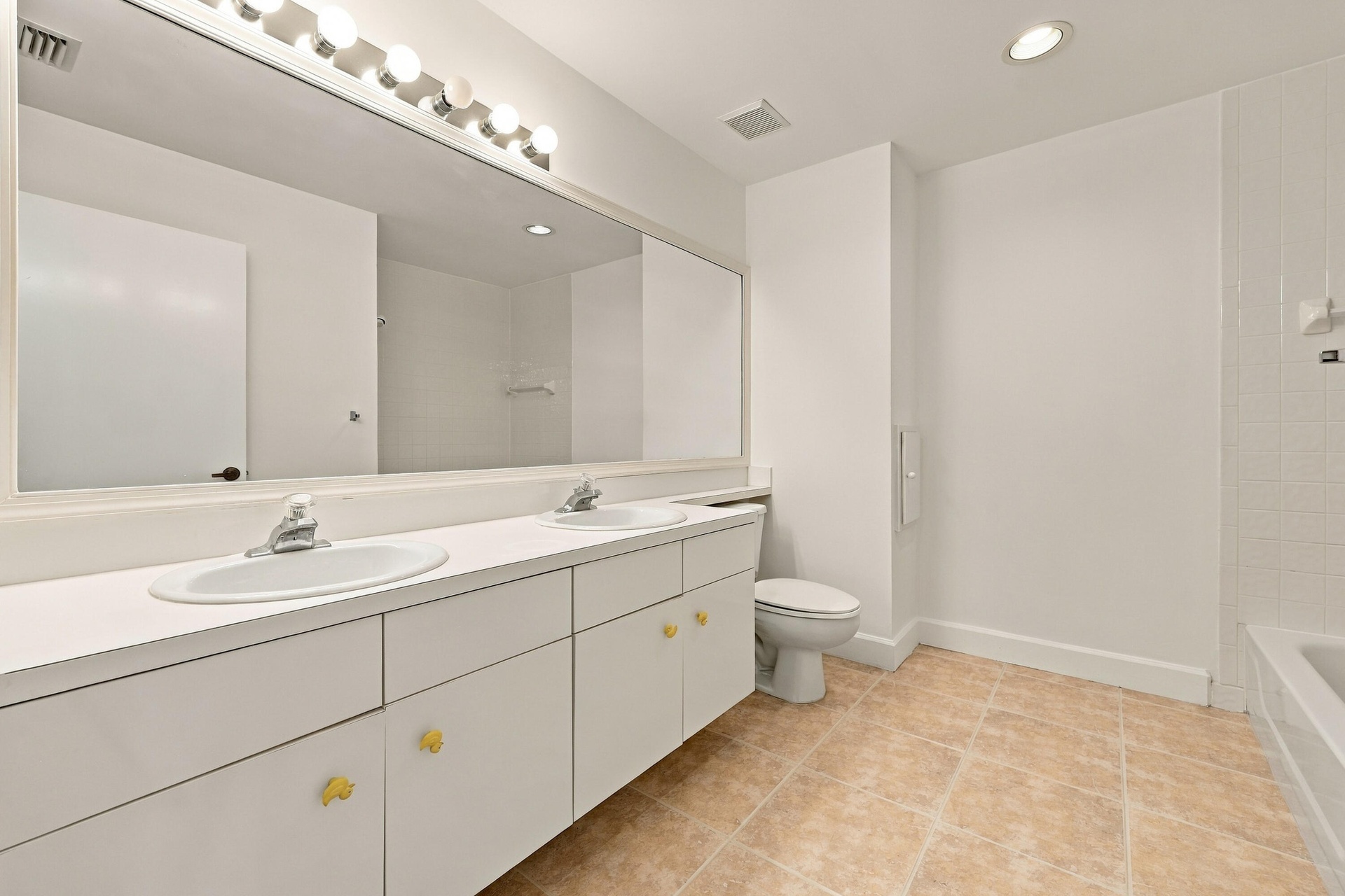 This well-appointed upstairs bathroom features an expansive dual-sink vanity, generous counter space, abundant cabinetry, and a large mirror with over