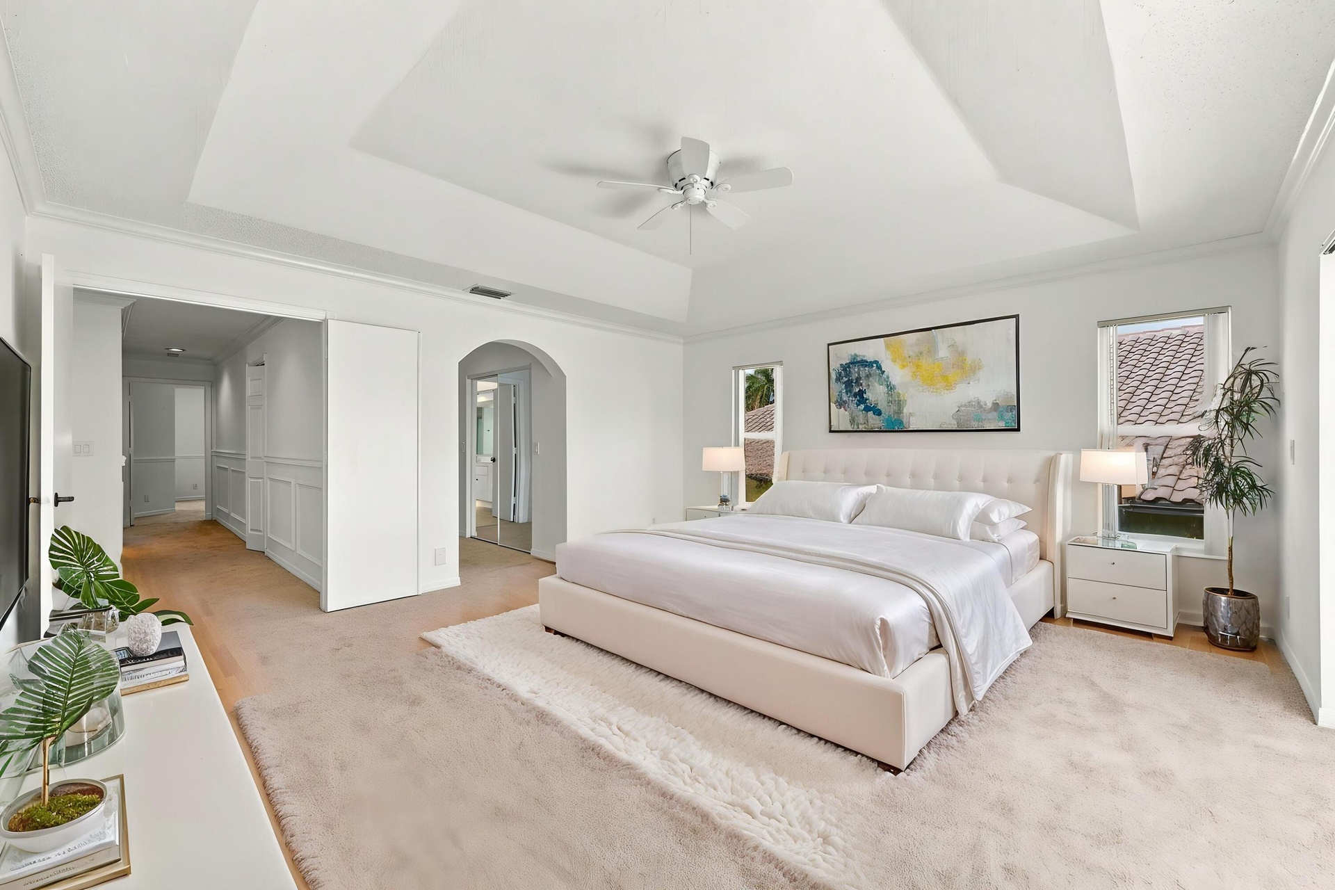 An impressive primary bedroom featuring a decorative tray ceiling, generous proportions, and a private entrance to the adjoining bathroom and dressing