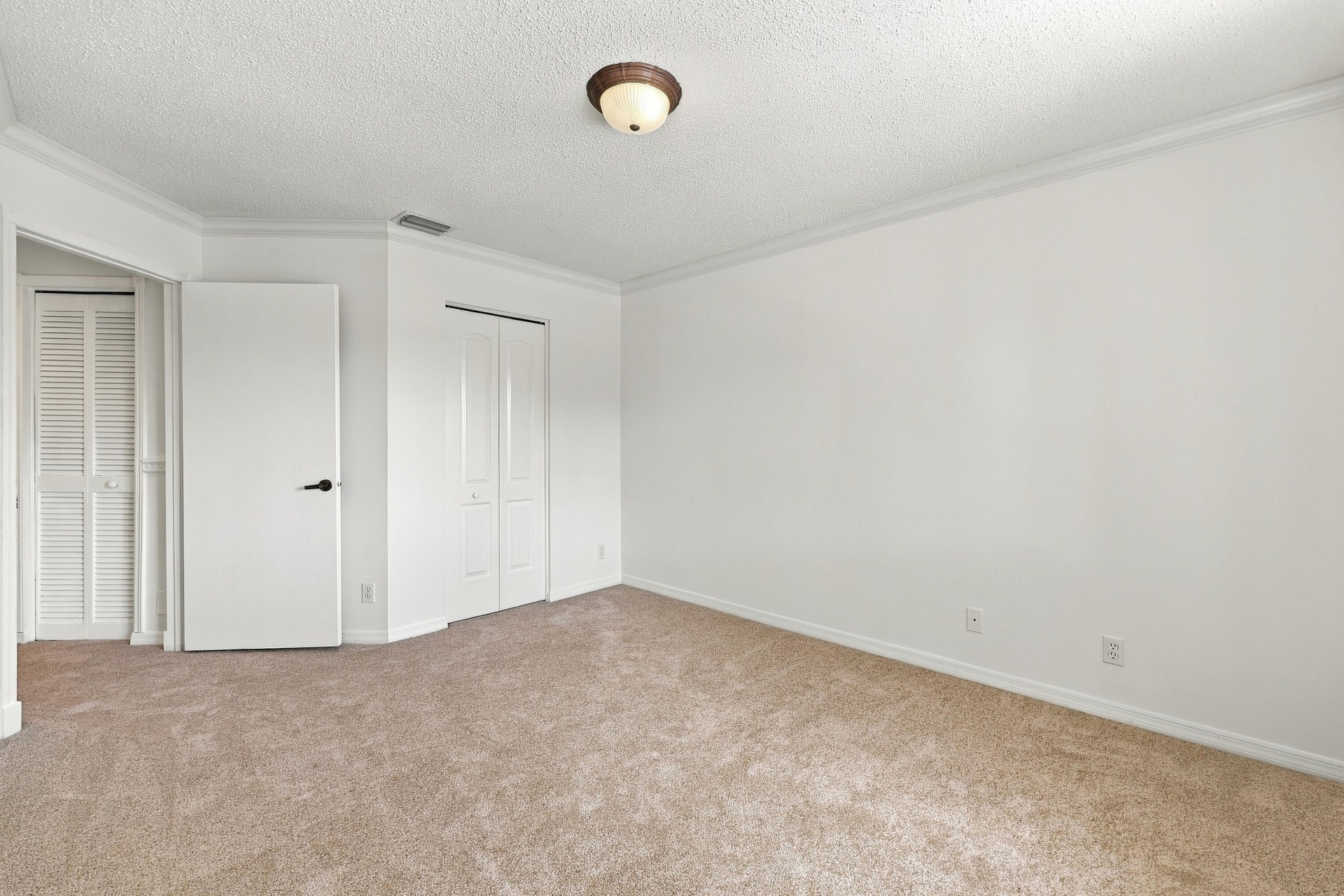 This inviting fourth bedroom features plush carpeting, neutral finishes, decorative crown molding, and a generous layout offering plenty of flexibilit