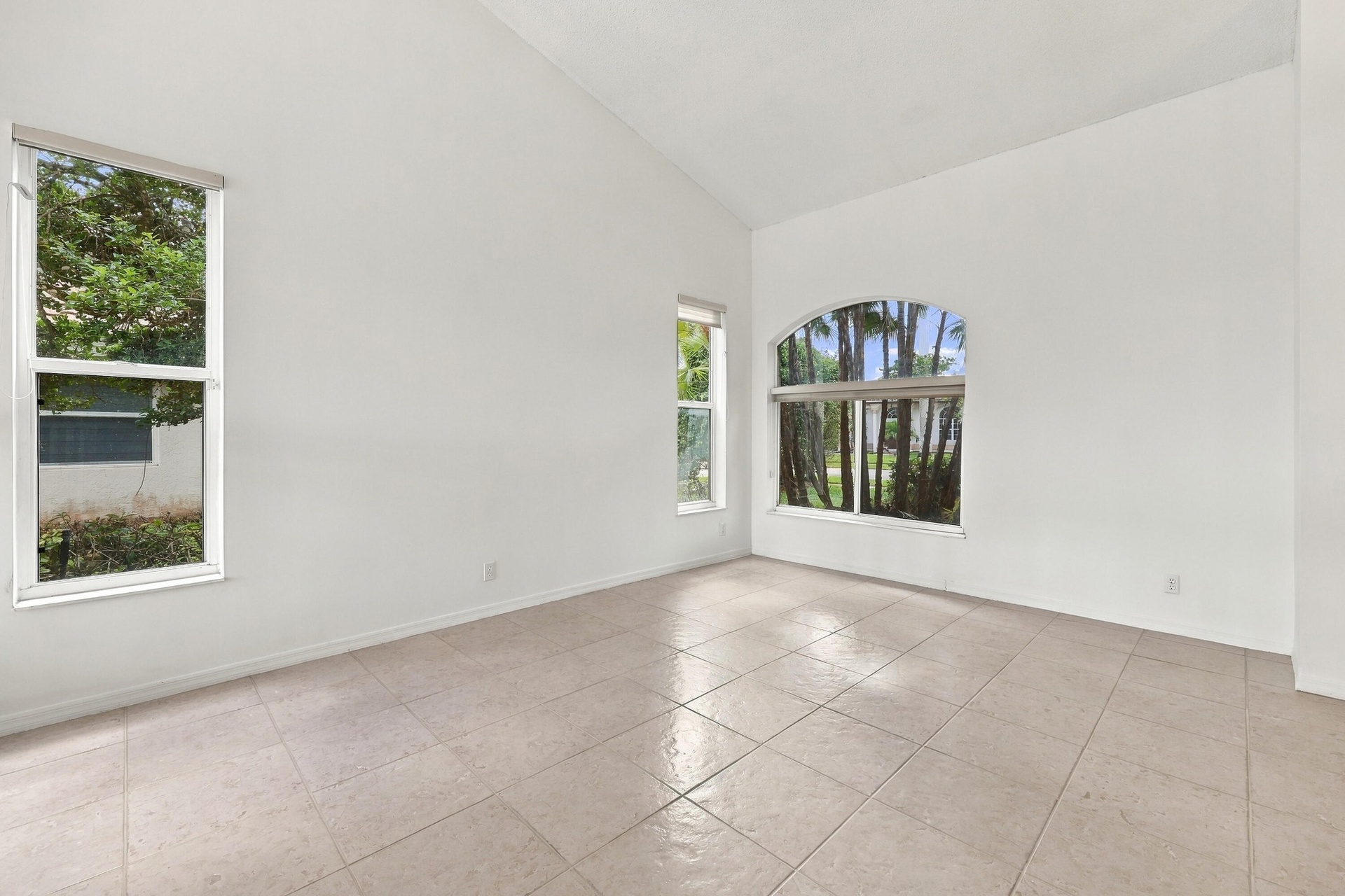 Soaring vaulted ceilings, expansive windows, and abundant natural light create a bright, inviting formal living room with an impressive sense of space