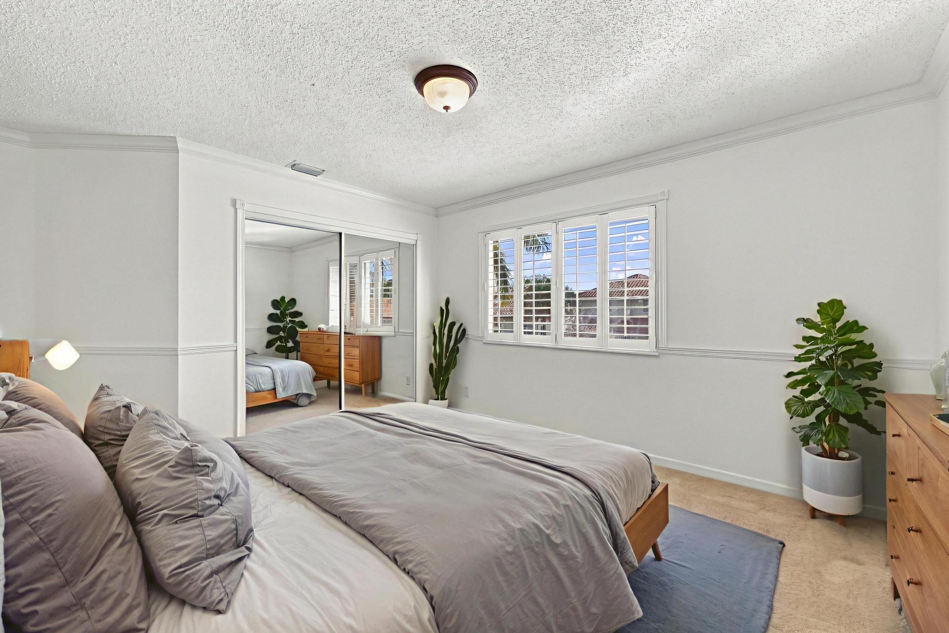 This generously sized third bedroom features plush carpeting, plantation shutters, mirrored closet doors, and decorative wall molding that adds charac