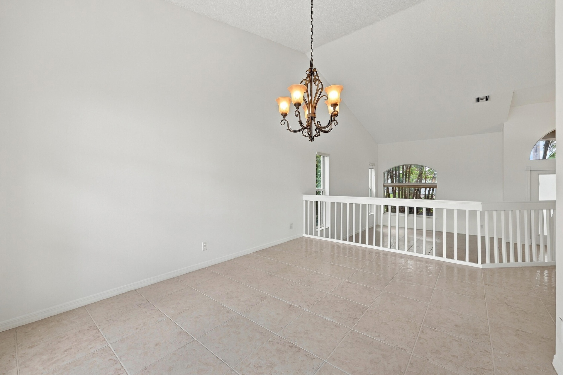 A decorative chandelier, dramatic arched window, and vaulted ceilings provide an elegant setting for both intimate dinners and larger celebrations.