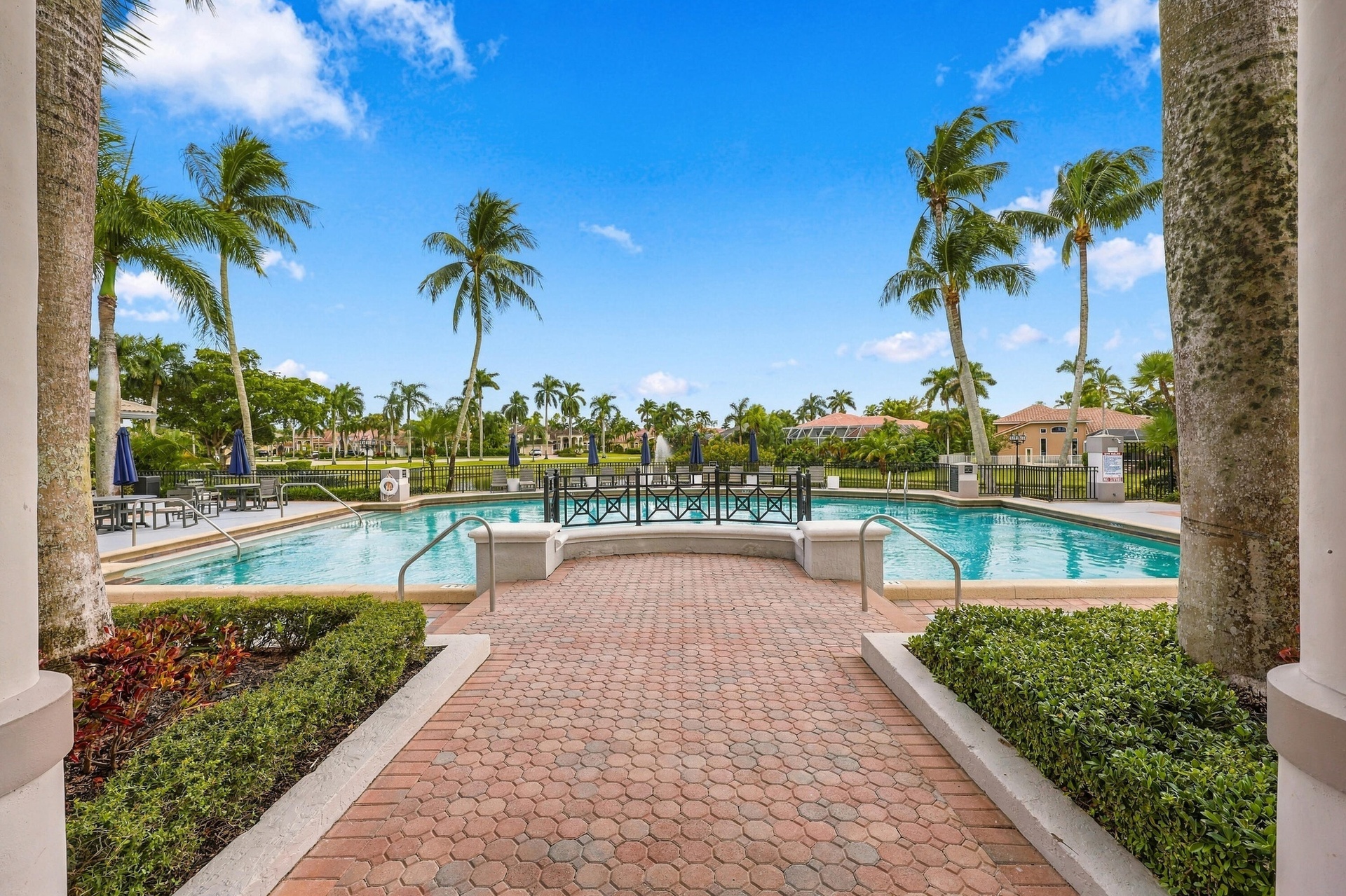 Experience resort-style living at the beautiful community swimming pool, surrounded by swaying palms, expansive lounging areas, and the impressive Boc
