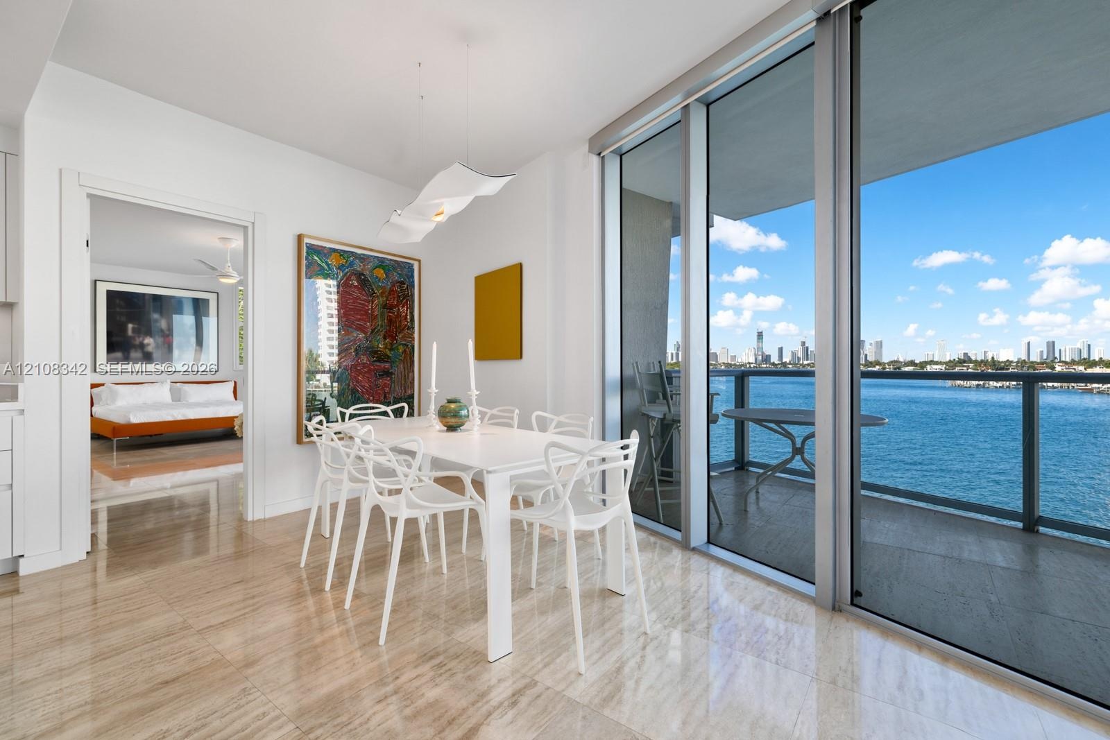 Floor-to-ceiling sliding glass doors, private balcony with metal railing, polished stone flooring, and sculptural pendant lighting