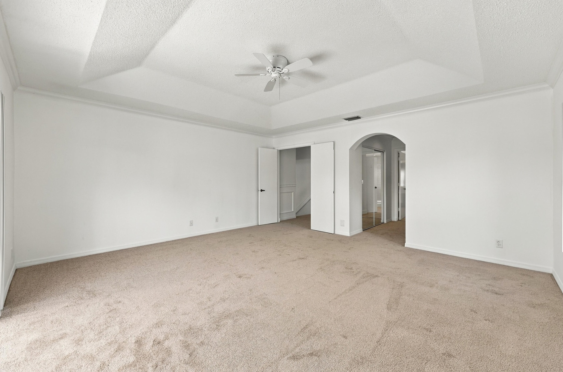 This generously sized primary suite offers an elegant tray ceiling, plush carpeting, and an expansive layout with plenty of room to create your own pe
