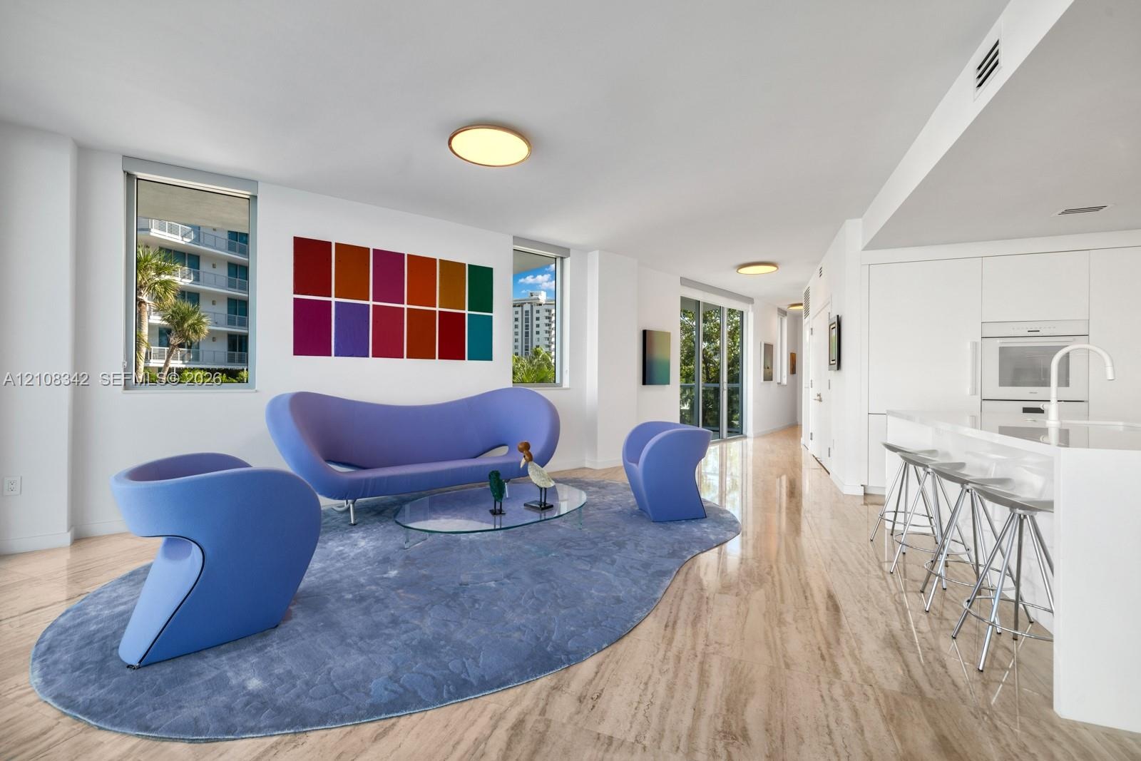 Open-concept interior featuring natural stone flooring, flush-mount circular lighting, expansive windows, and built-in minimalist cabinetry with integ
