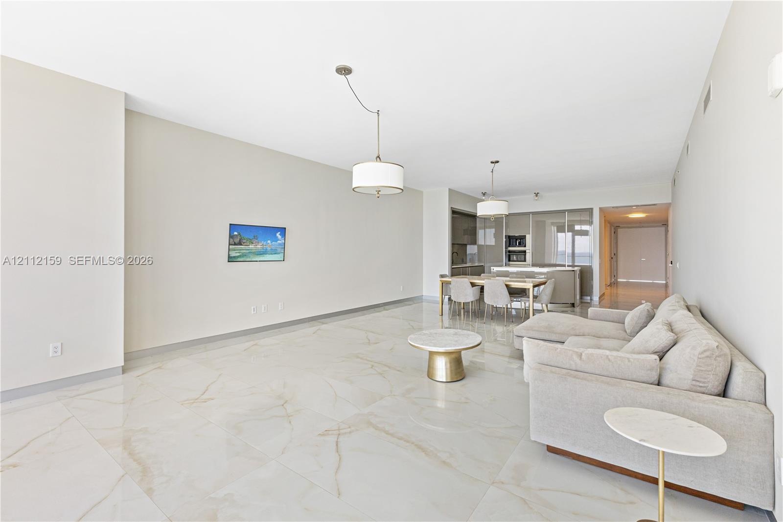 Large-format neutral flooring with veining, dual modern drum pendant lighting, and built-in kitchen cabinetry