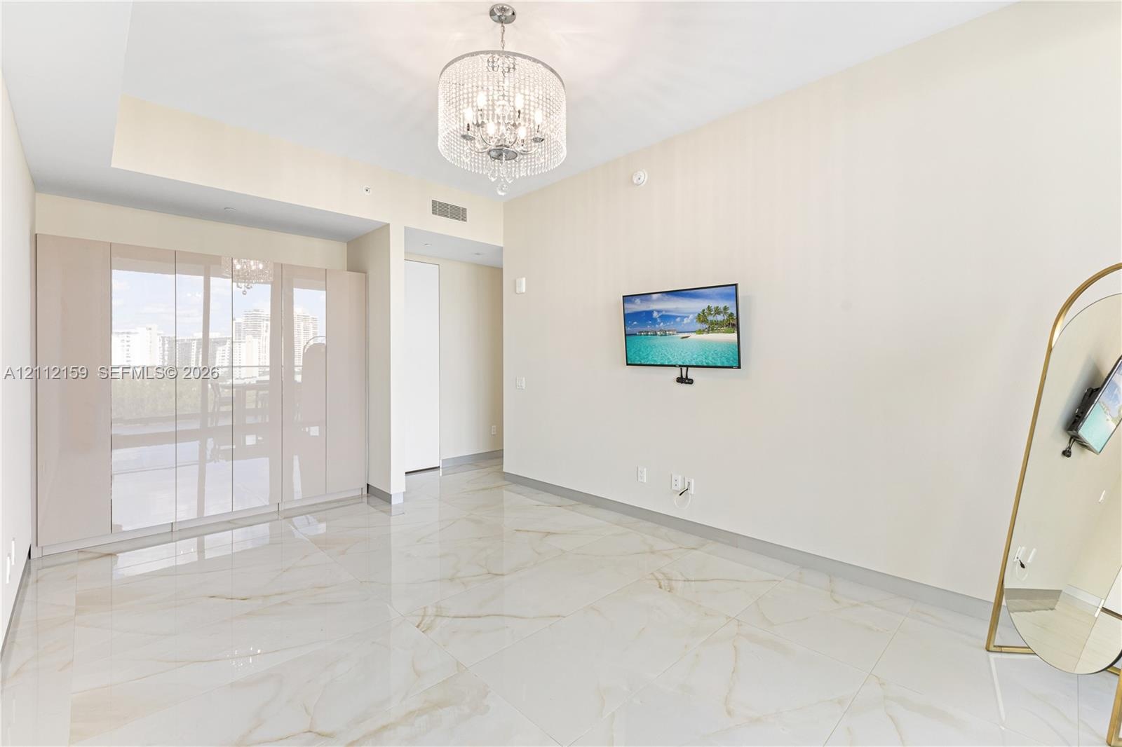 Polished stone flooring, floor-to-ceiling glass wall panels, and an ornate crystal chandelier